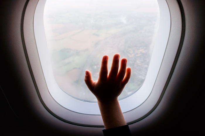 Ventana de avión con la mano de un niño